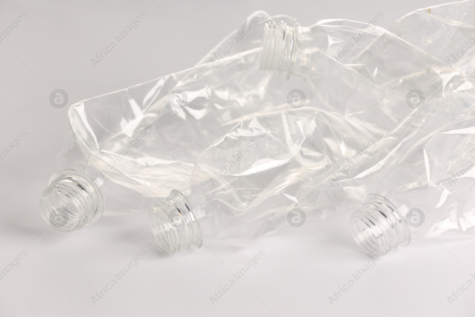 Photo of Crumpled disposable plastic bottles on white background