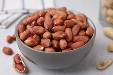 Fresh unpeeled peanuts in bowl on grey table, closeup