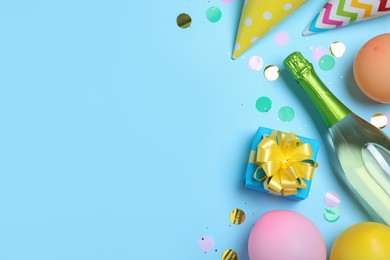Photo of Flat lay composition with birthday decor and bottle of sparkling wine on light blue background, space for text