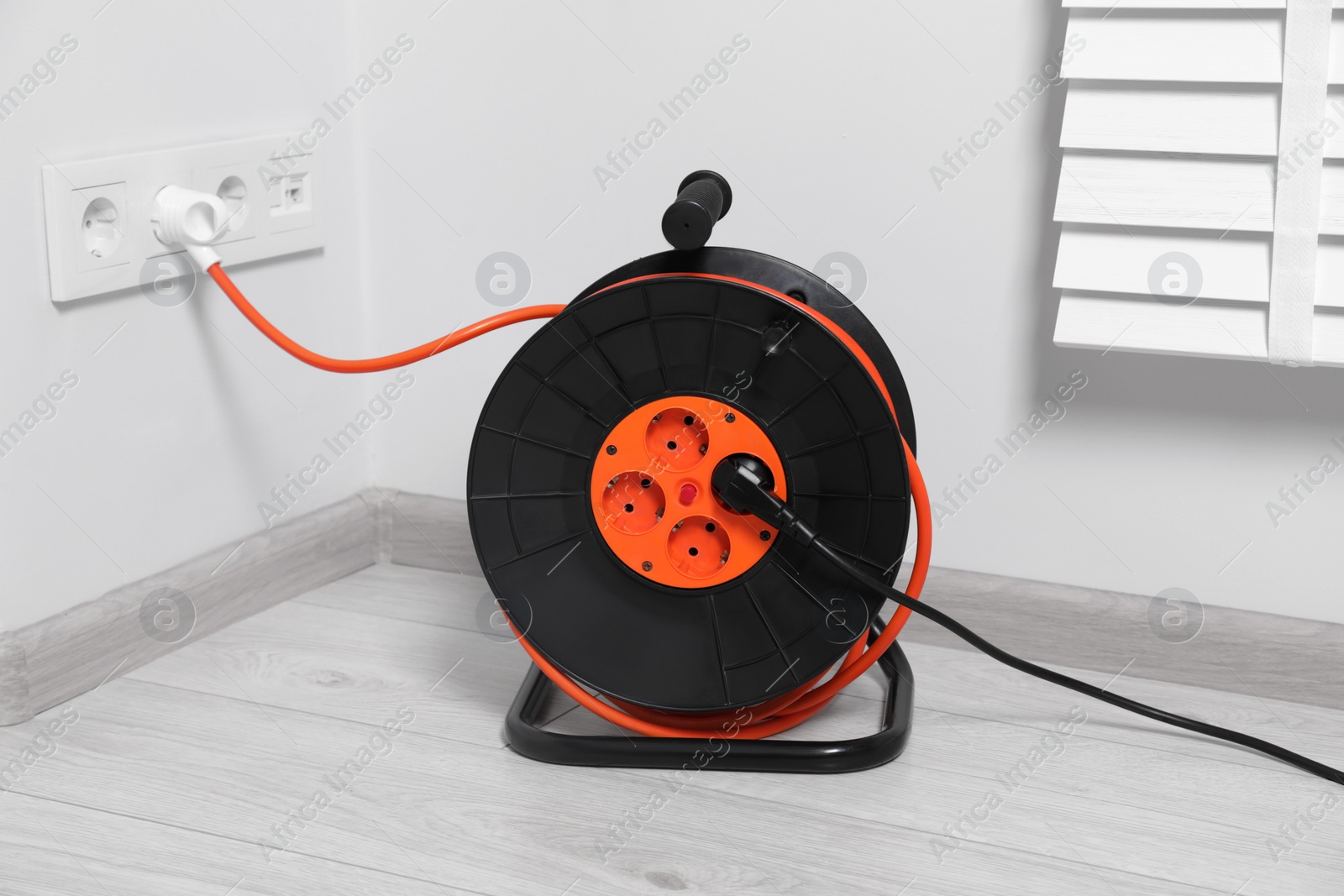Photo of Extension cord reel plugged into socket indoors. Electrician's equipment