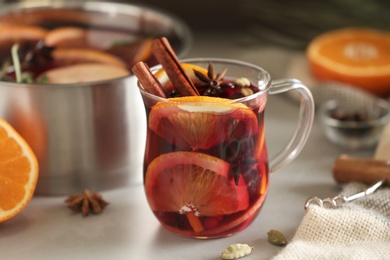 Photo of Glass cup of tasty mulled wine on grey table