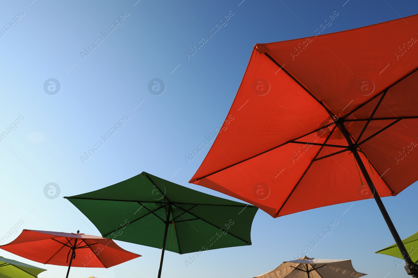 Photo of Colorful beach umbrellas against blue sky on sunny day