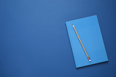Photo of Notebook and pencil on bright background, top view with space for text. Color of the year 2020 (Classic blue)