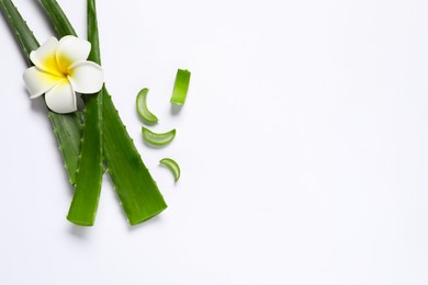 Cut aloe vera leaves and plumeria flower on white background, flat lay. Space for text