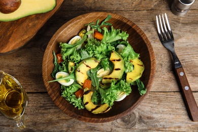 Photo of Delicious avocado salad with boiled eggs in bowl on wooden table, flat lay