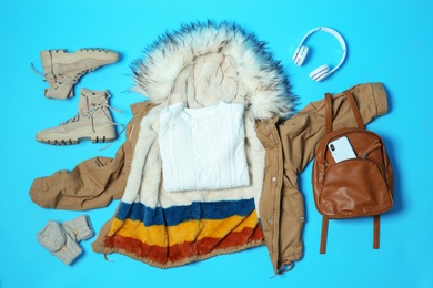 Flat lay composition with warm clothes for winter vacation on color background