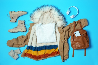 Photo of Flat lay composition with warm clothes for winter vacation on color background