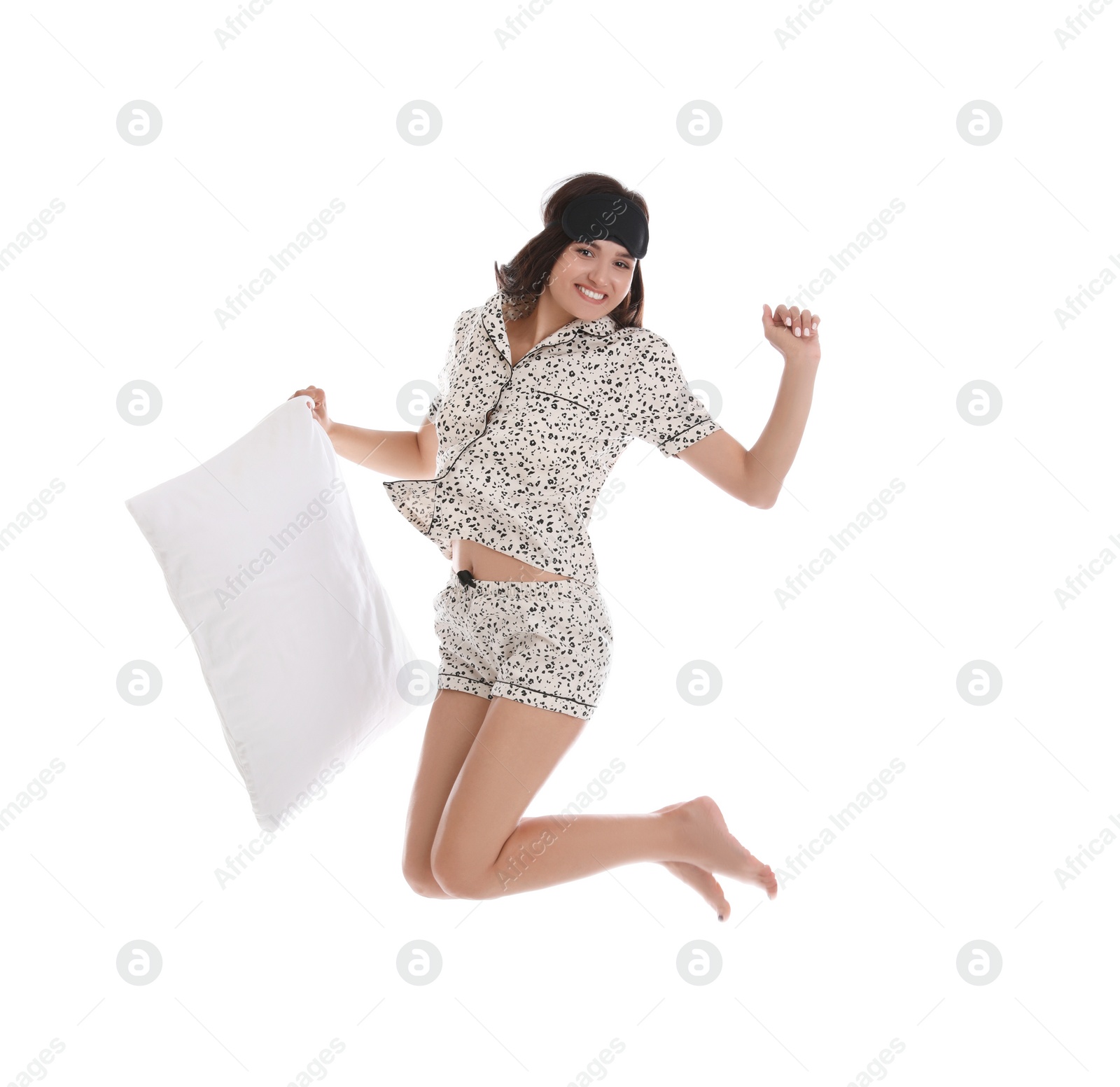 Photo of Beautiful woman with pillow jumping on white background. Bedtime