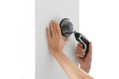 Technician installing CCTV camera on wall indoors, closeup