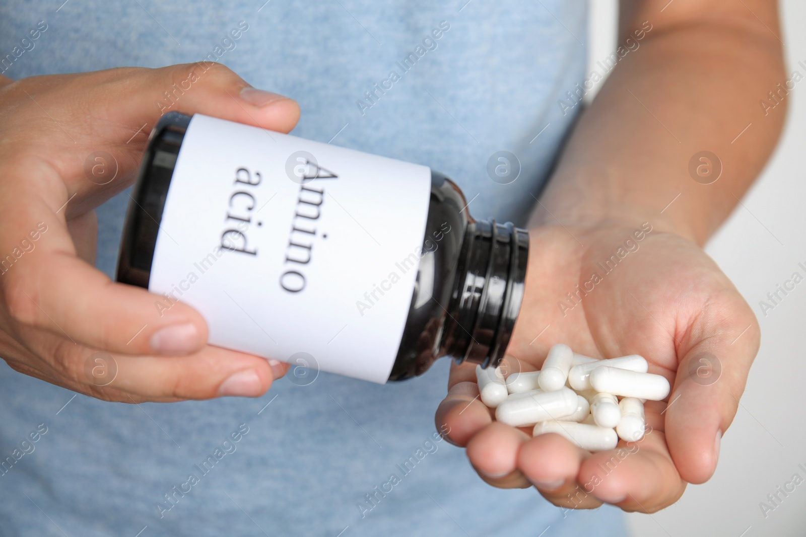 Photo of Man with amino acids pills on light background, closeup