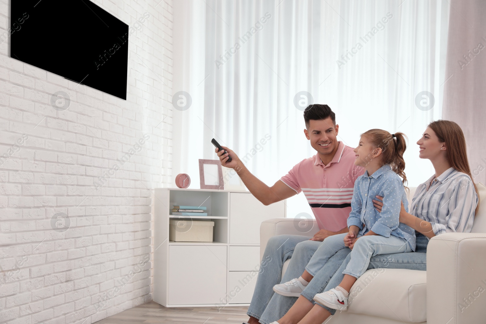 Photo of Happy family watching TV on sofa at home