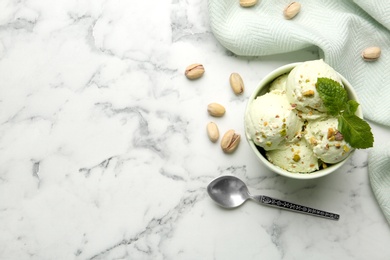 Photo of Tasty pistachio ice cream served on white marble table, flat lay. Space for text
