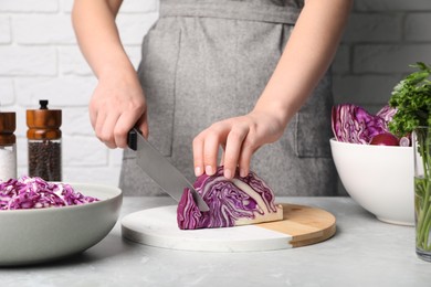 Photo of Woman shredding fresh red cabbage at light grey table, closeup
