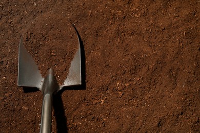 Photo of Metal shovel on fertile soil, top view and space for text. Gardening tool