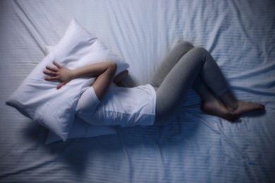 Photo of Young woman suffering from insomnia in bed, top view