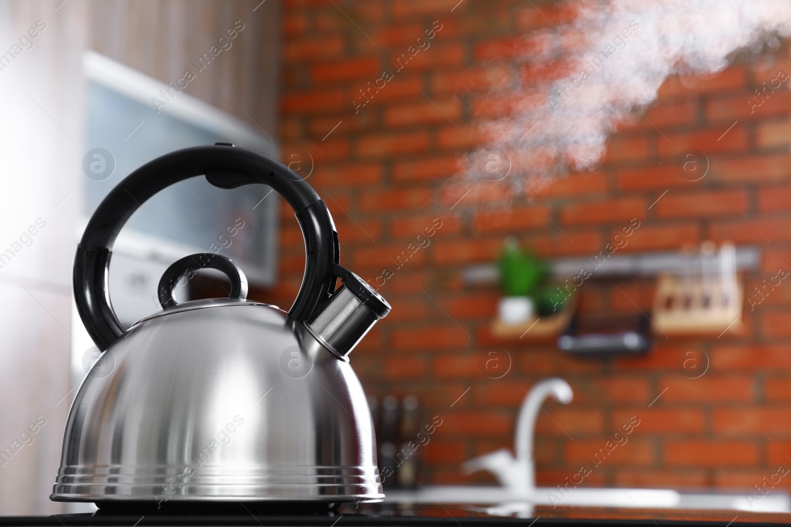 Photo of Modern kettle with whistle on stove in kitchen, space for text