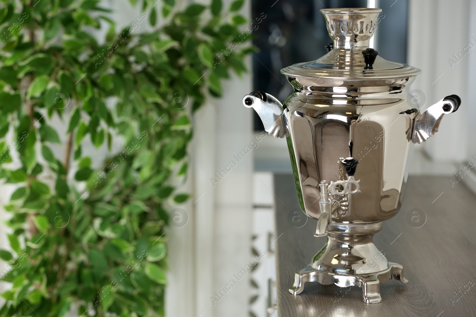 Photo of Metal samovar on wooden countertop in kitchen, space for text. Russian tea culture