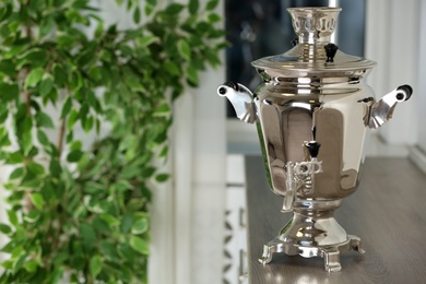 Metal samovar on wooden countertop in kitchen, space for text. Russian tea culture