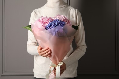 Photo of Woman with bouquet of beautiful hortensia flowers near grey wall, closeup