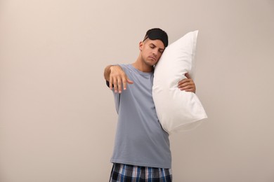 Photo of Somnambulist with soft pillow on beige background. Sleepwalking