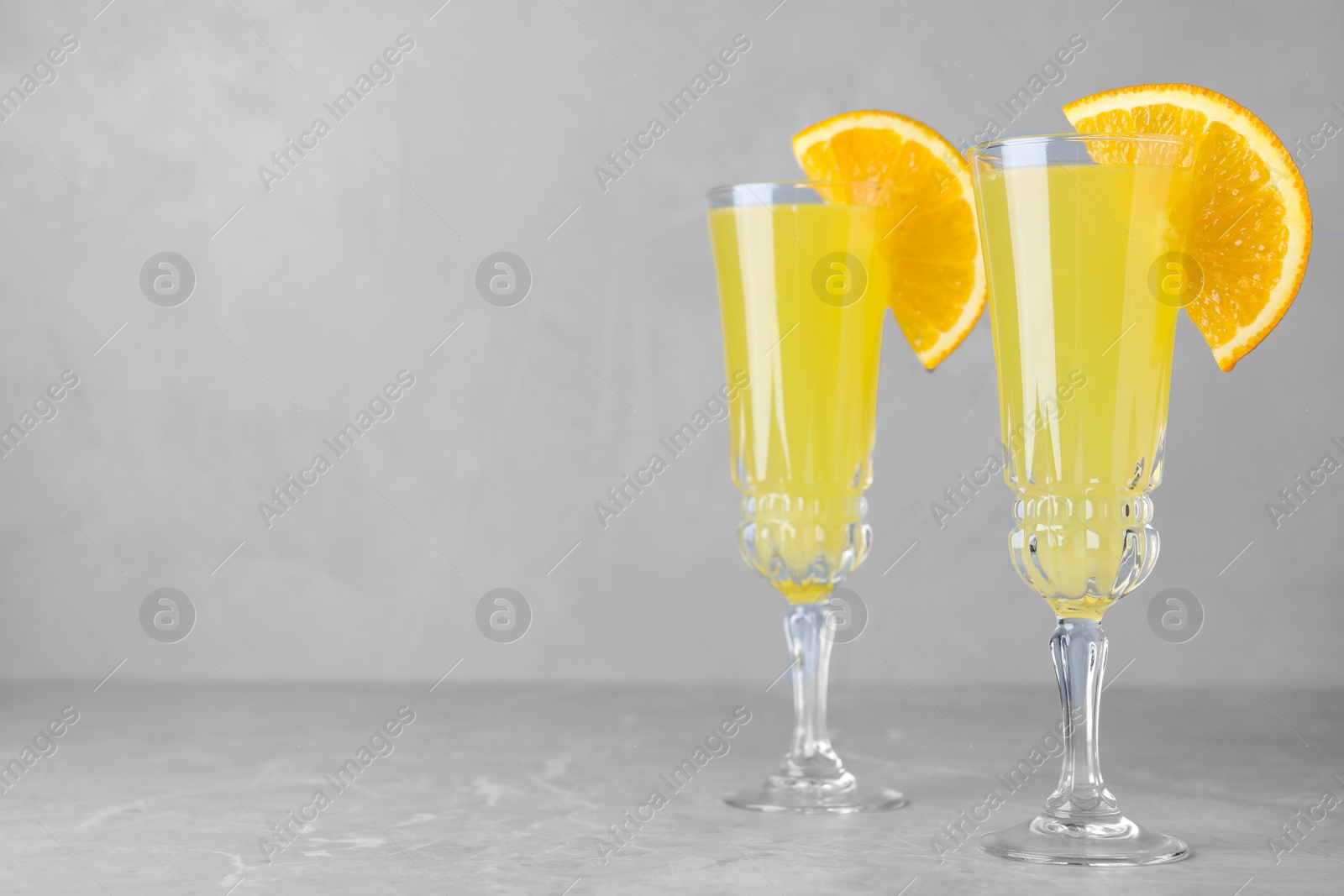 Photo of Glasses of Mimosa cocktail with garnish on marble table. Space for text