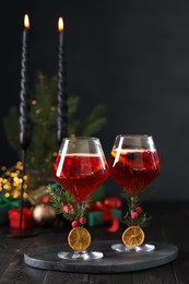Christmas Sangria cocktail in glasses and burning candles on dark wooden table