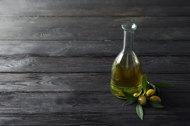 Photo of Bottle with fresh olive oil on wooden table