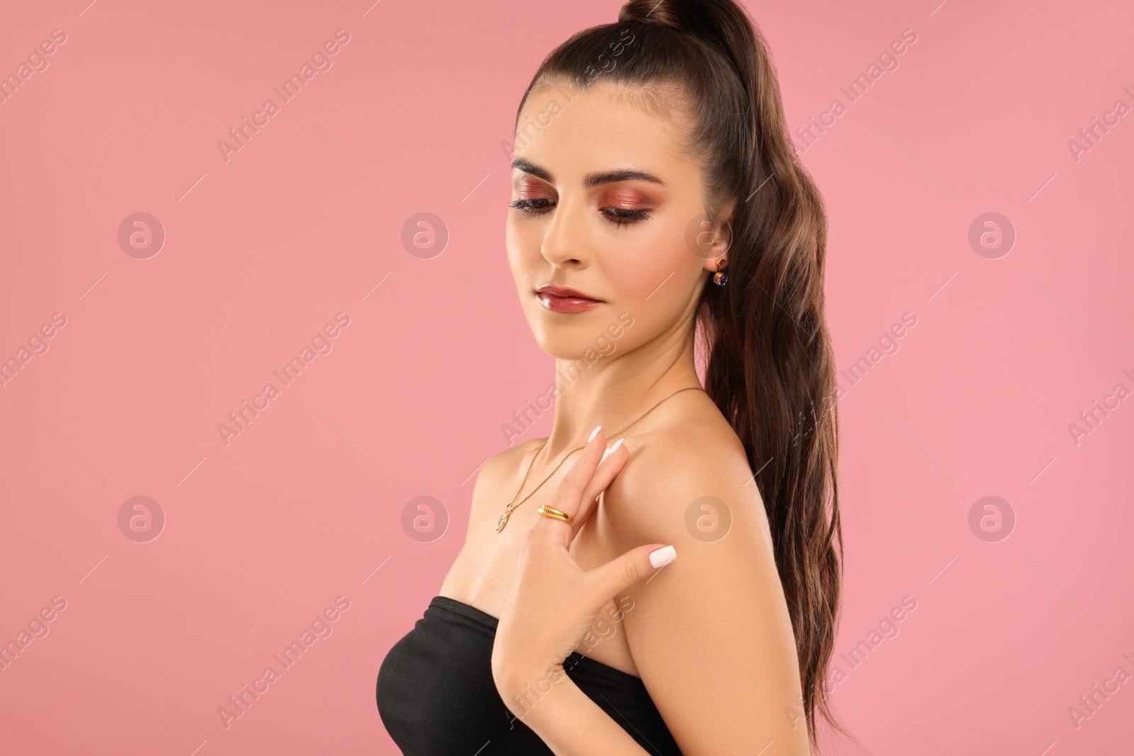 Photo of Beautiful woman with elegant jewelry on pink background, space for text