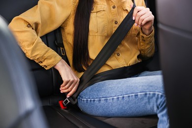 Photo of Woman fastening safety seat belt inside modern car, closeup