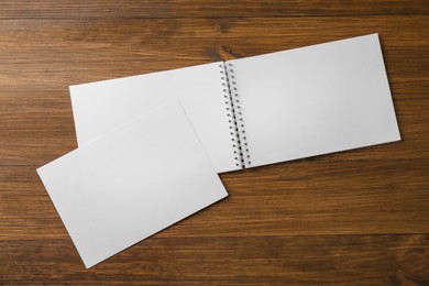 Photo of Sheet of paper and blank brochure on wooden table, flat lay. Mockup for design