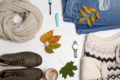 Photo of Stylish outfit and autumn leaves on white wooden background, flat lay. Trendy warm clothes