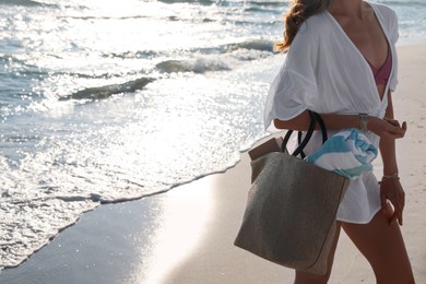 Photo of Woman carrying bag with beach towel near sea, closeup