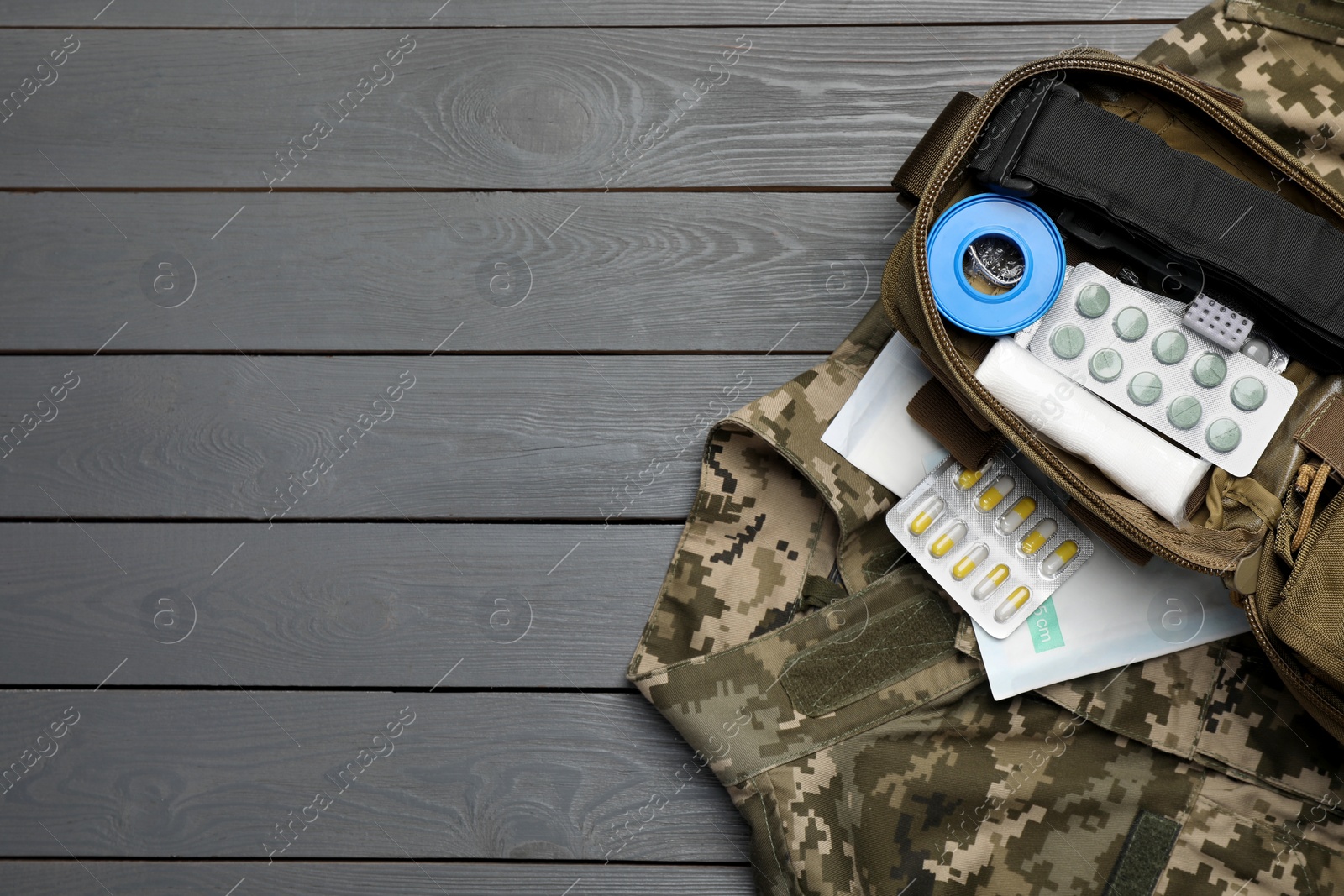 Photo of Military first aid kit and uniform on wooden table, flat lay. Space for text