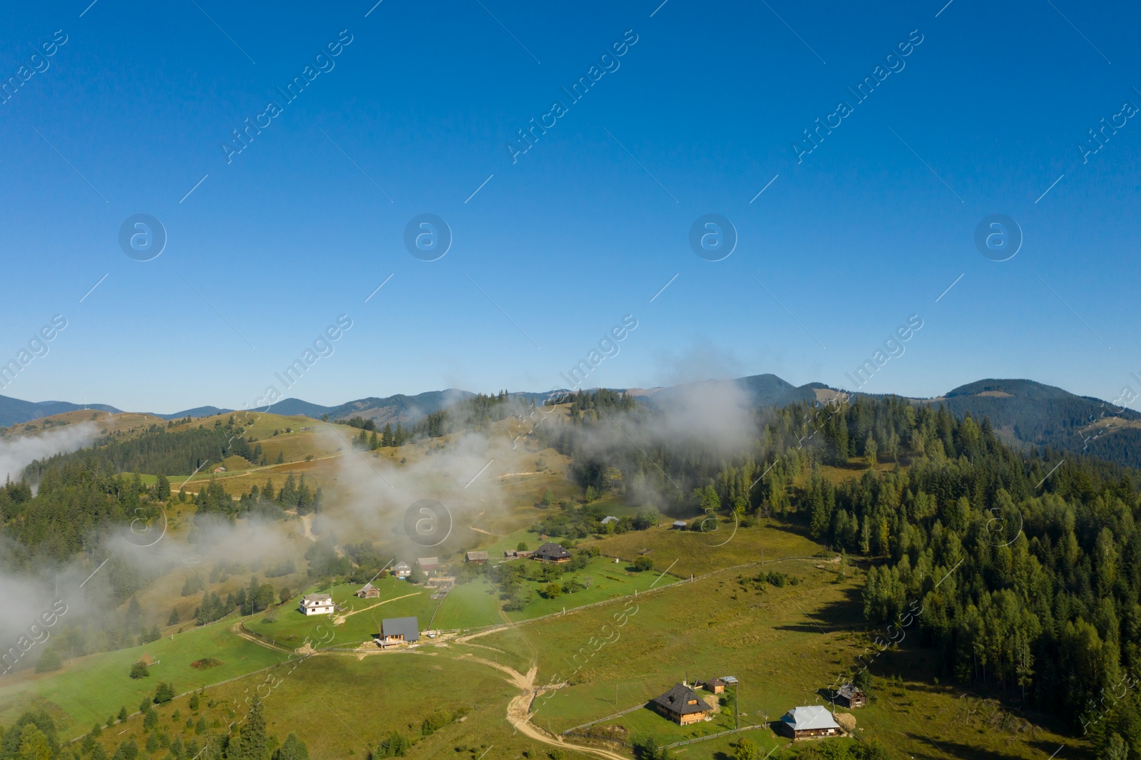 Image of Aerial view of beautiful landscape with misty forest and village in mountains