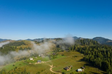 Image of Aerial view of beautiful landscape with misty forest and village in mountains