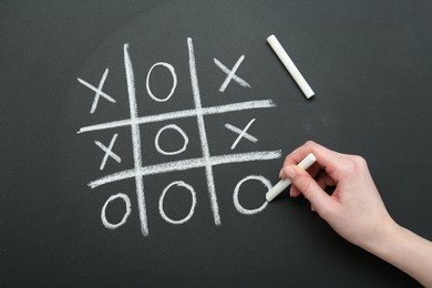 Photo of Woman playing tic tac toe on chalkboard, closeup