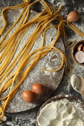Homemade pasta, flour and eggs on dark table, flat lay