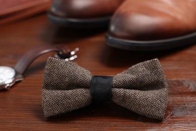 Photo of Stylish brown bow tie on wooden background, closeup