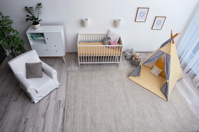 Photo of Cozy baby room interior with play tent and toys, above view