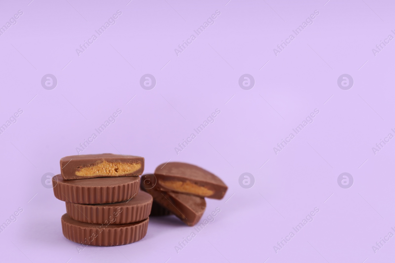 Photo of Sweet peanut butter cups on violet background. Space for text