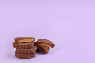 Photo of Sweet peanut butter cups on violet background. Space for text