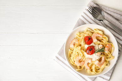 Photo of Delicious pasta with shrimps served on white wooden table, top view. Space for text