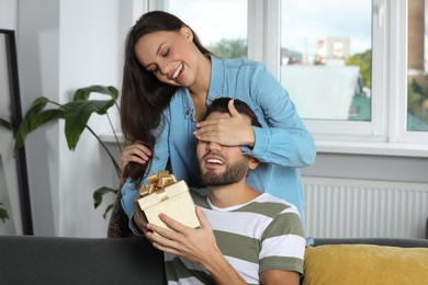 Photo of Woman presenting gift to her boyfriend at home