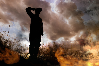 Image of Silhouette of soldier saluting on battlefield. Military service