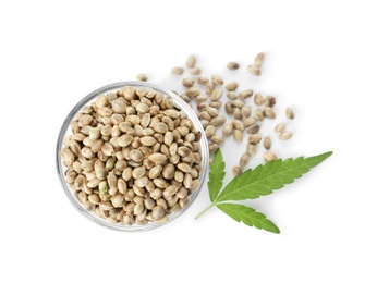 Photo of Bowl of hemp seeds with green leaf on white background, top view