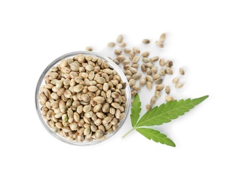 Bowl of hemp seeds with green leaf on white background, top view