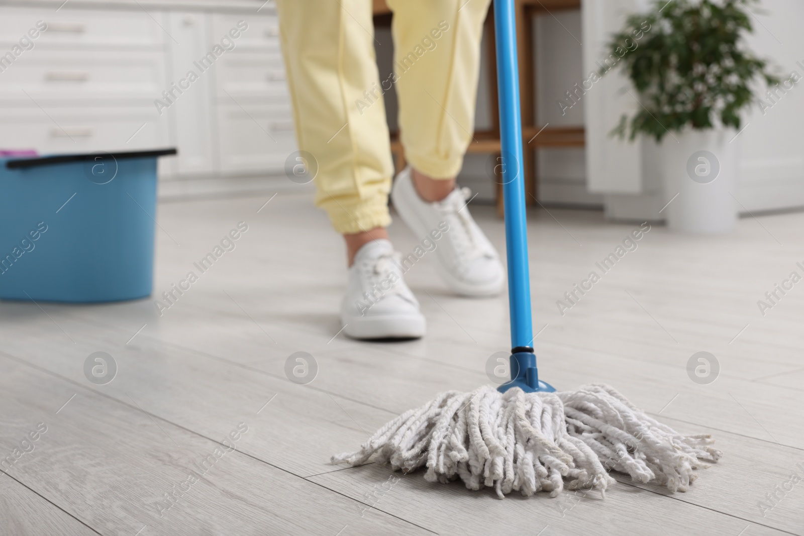 Photo of Woman cleaning floor with mop indoors, selective focus