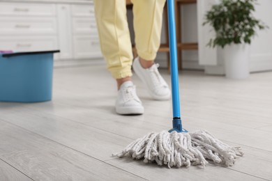 Photo of Woman cleaning floor with mop indoors, selective focus