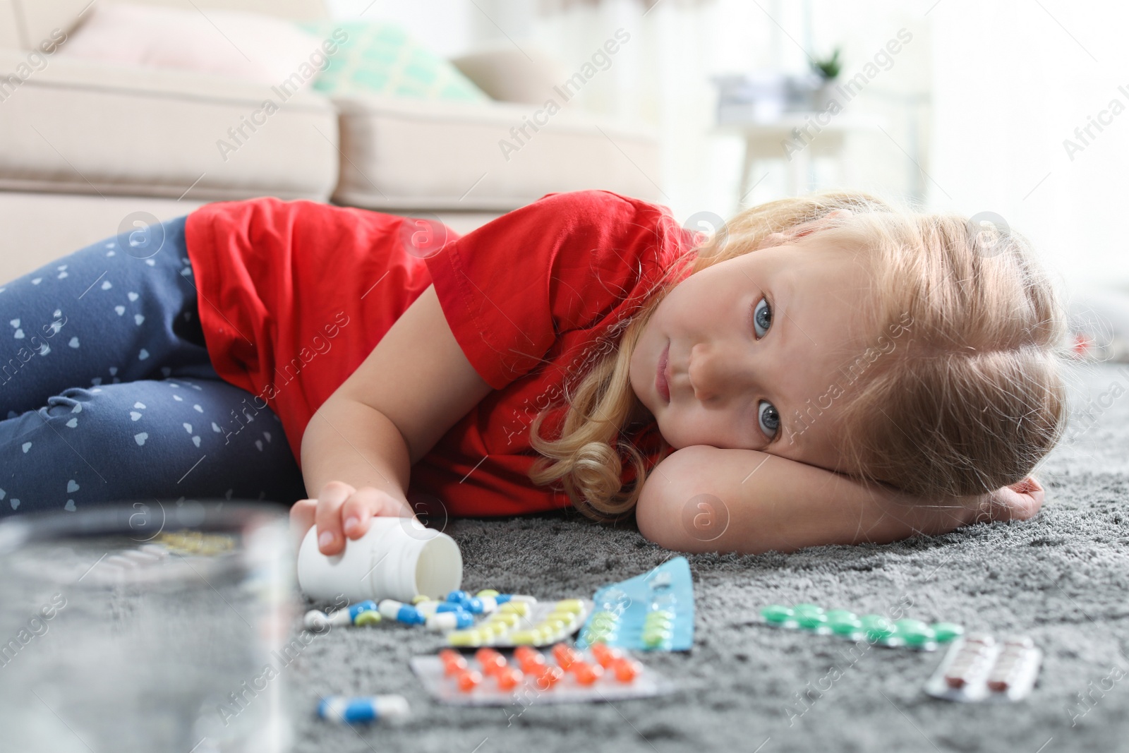 Photo of Little child with many different pills on floor at home. Danger of medicament intoxication