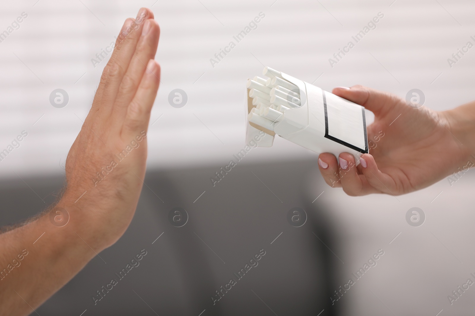 Photo of Stop smoking concept. Man refusing cigarettes on blurred background, closeup